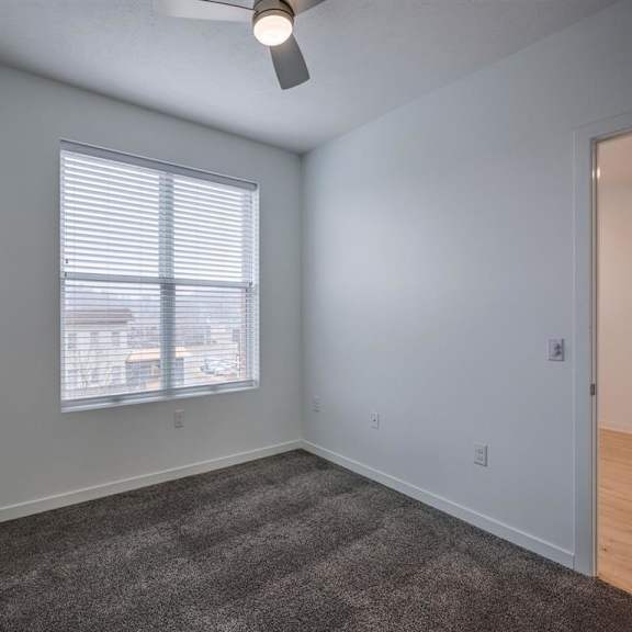 a room with a carpeted floor and a window with blinds.