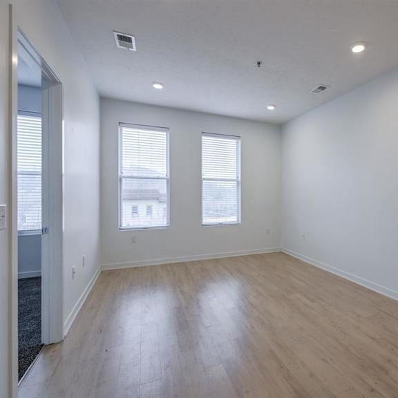 a room with wooden flooring and two windows.