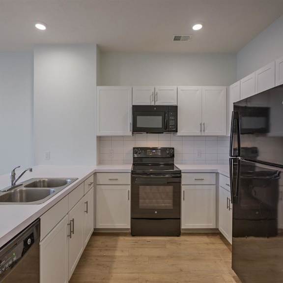 a kitchen with white cabinets and black appliances.
