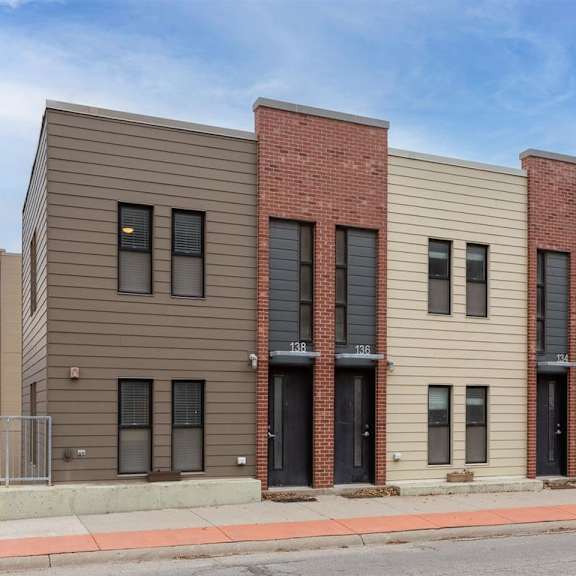 a row of modern townhouses with brick accents and black doors.