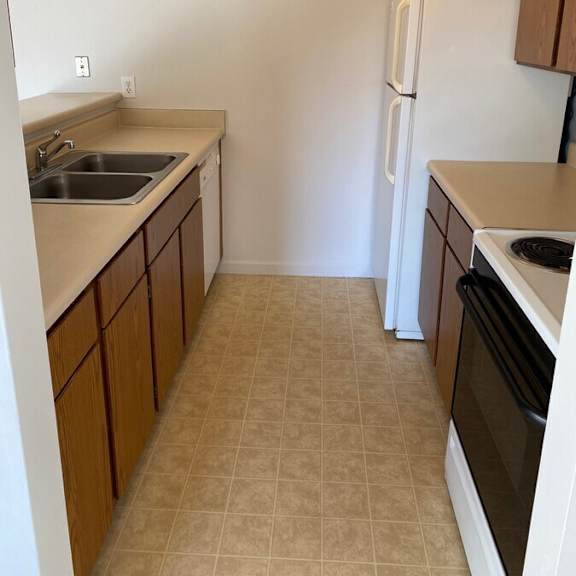 a kitchen with a white refrigerator, black oven, and brown cabinets.