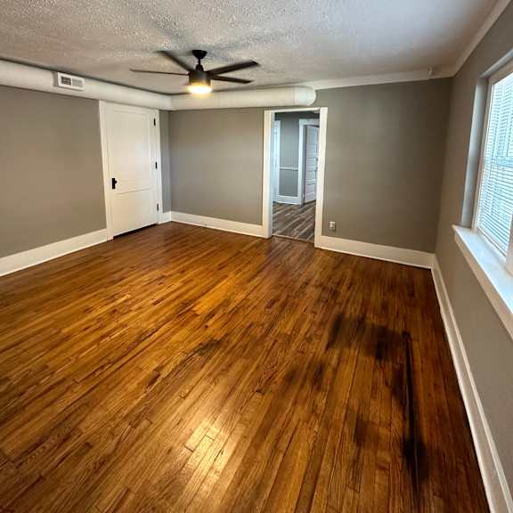 a room with a ceiling fan and wooden flooring.