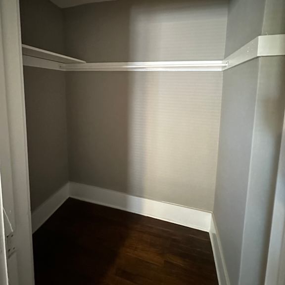 a white closet with a white door and a white shelf.
