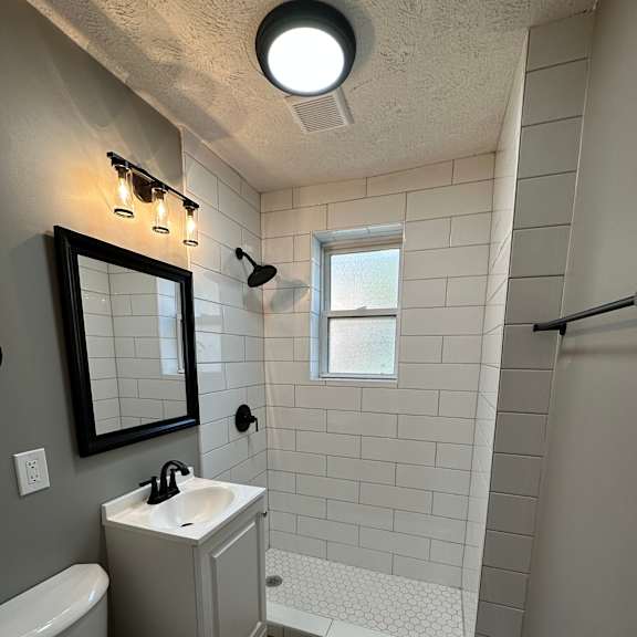 a bathroom with a toilet, sink, and mirror.