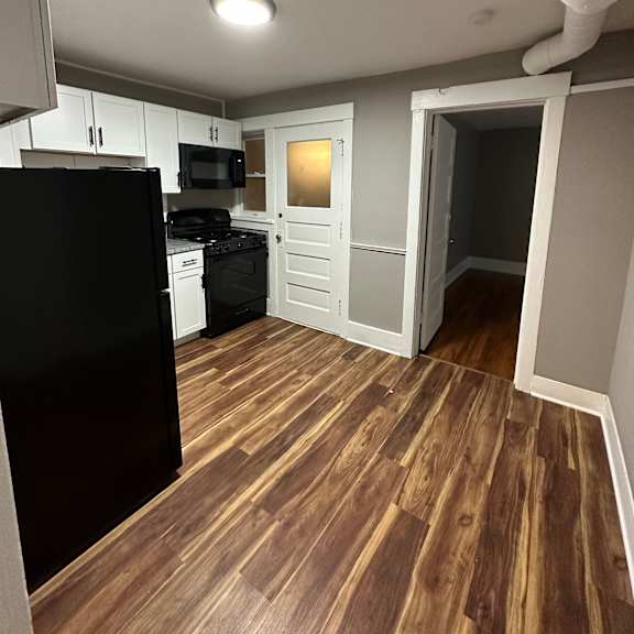 a kitchen with black appliances and wooden floors.