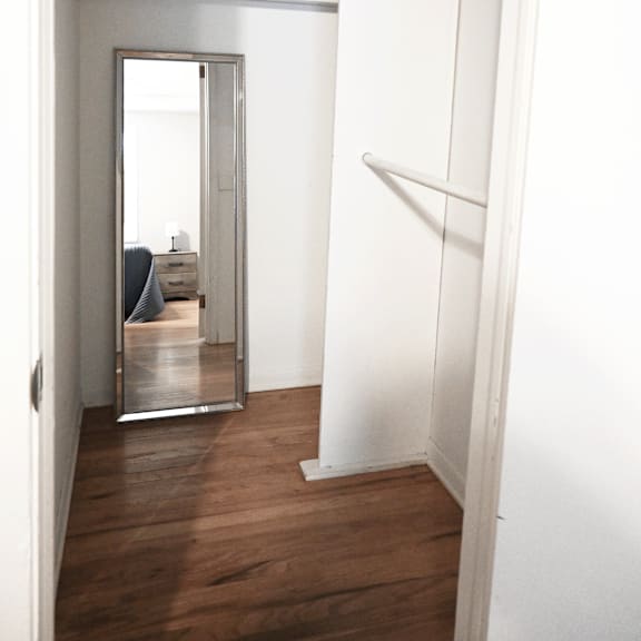 a mirror on the wall reflects a bedroom with a bed and a dresser.