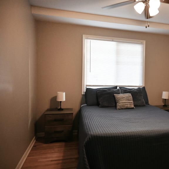 a bedroom with a bed, nightstands, and a ceiling fan.