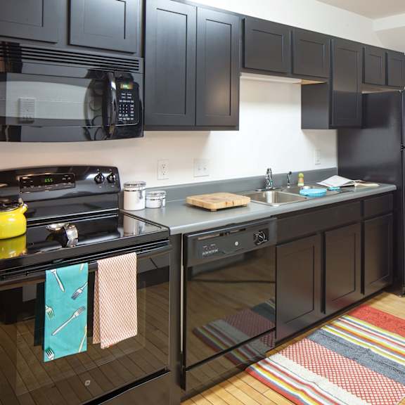 a kitchen with black cabinets and a wooden floor.