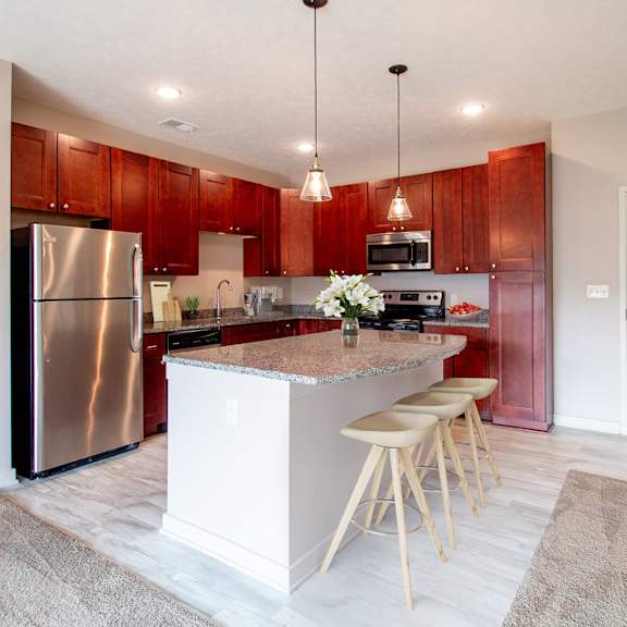 a kitchen with a white island and wooden stools.