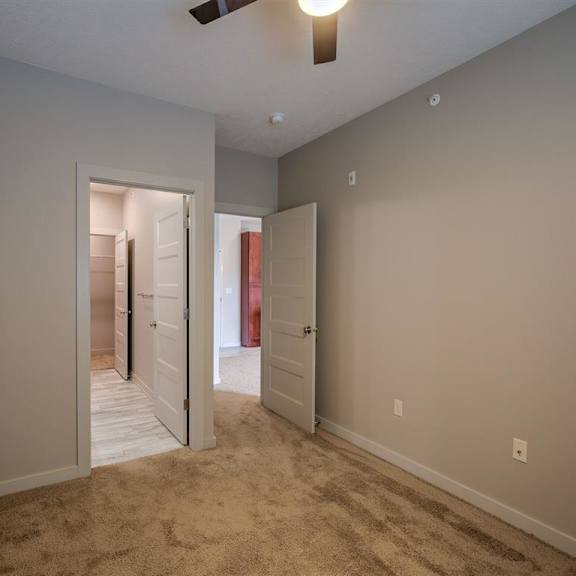 a room with a carpeted floor and a ceiling fan.