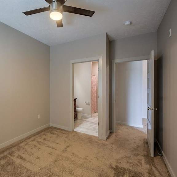 a room with a ceiling fan and carpeted floor.