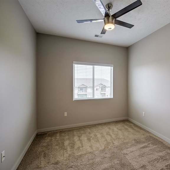 a room with a ceiling fan and a window.