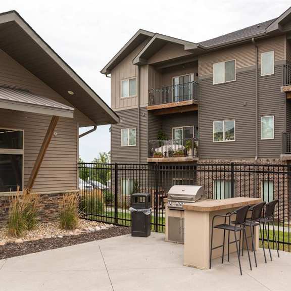 a patio with a table and chairs is in front of a two-story apartment building.