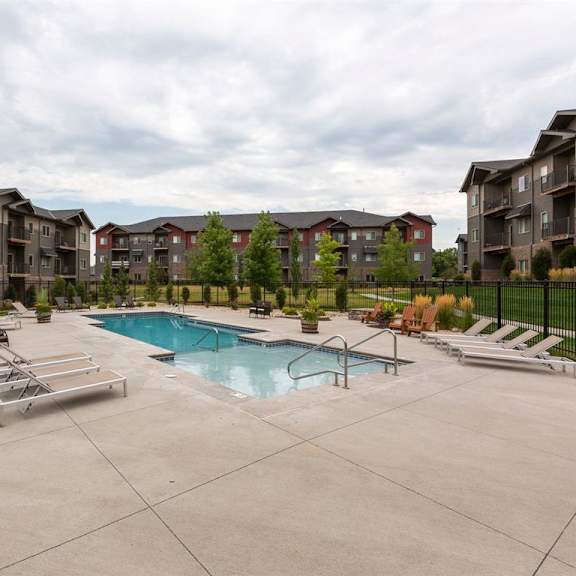 a swimming pool surrounded by lounge chairs in a residential area.