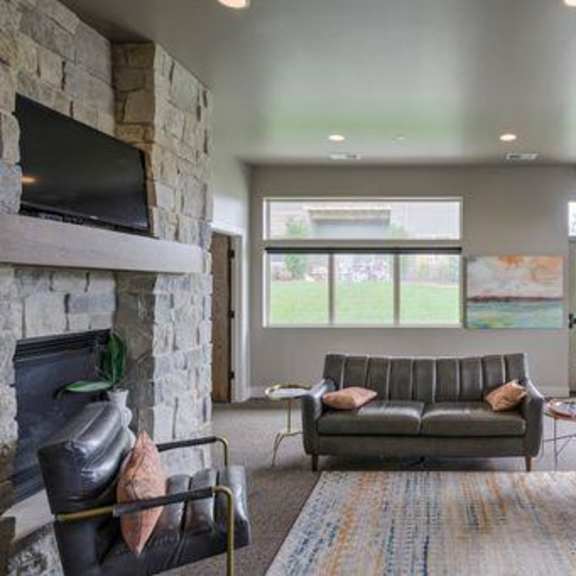 a living room with a grey couch, a fireplace, and a rug.