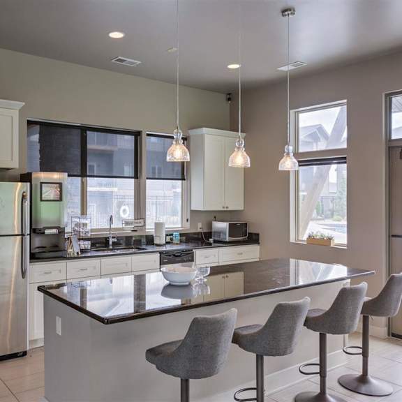 a modern kitchen with a large island and grey chairs.