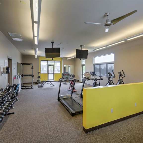 a gym with a variety of equipment including treadmills, weights, and exercise bikes.