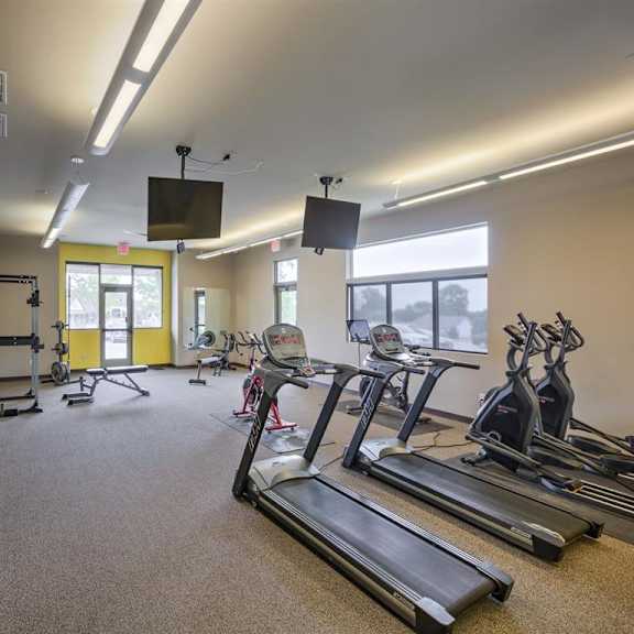 a gym with treadmills, elliptical machines, and other exercise equipment.