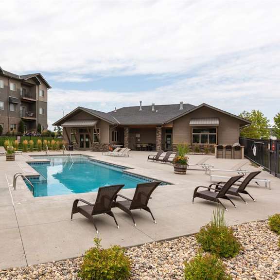 a large outdoor swimming pool surrounded by lounge chairs and plants.