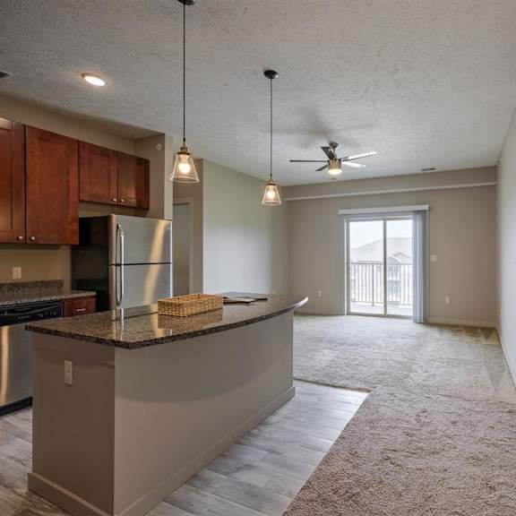 a spacious kitchen and living room with a ceiling fan and sliding glass doors.