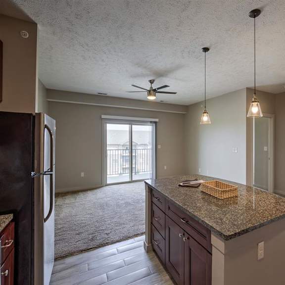 a kitchen with a black fridge and a fan on the ceiling.