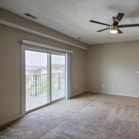 a spacious room with a ceiling fan and sliding glass doors.