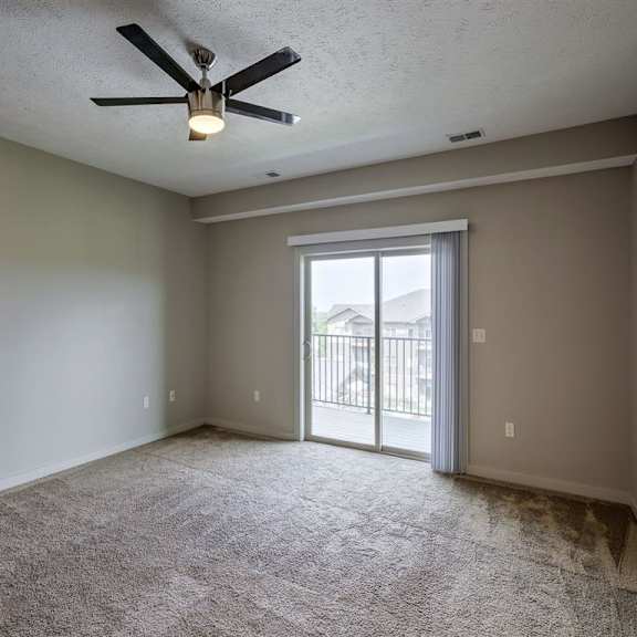a room with a ceiling fan and carpeted floor.