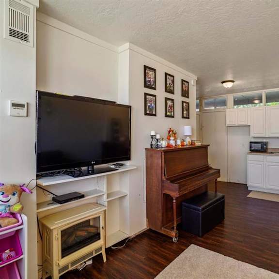 a living room with a television, a piano, and a fireplace.