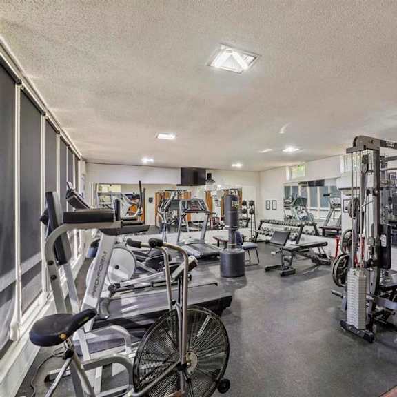 a gym with a variety of equipment including a stationary bike and a leg press machine.