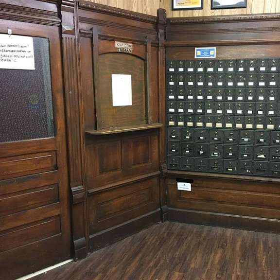 a wooden room with a mailbox and a wall of mailboxes.