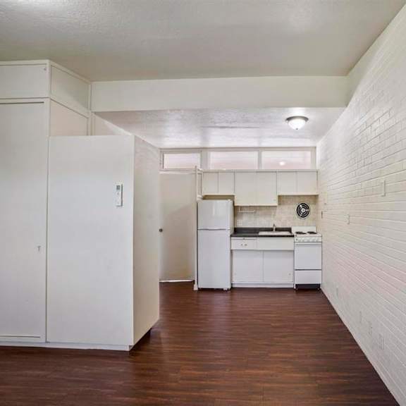 a kitchen with white cabinets and a white brick wall.