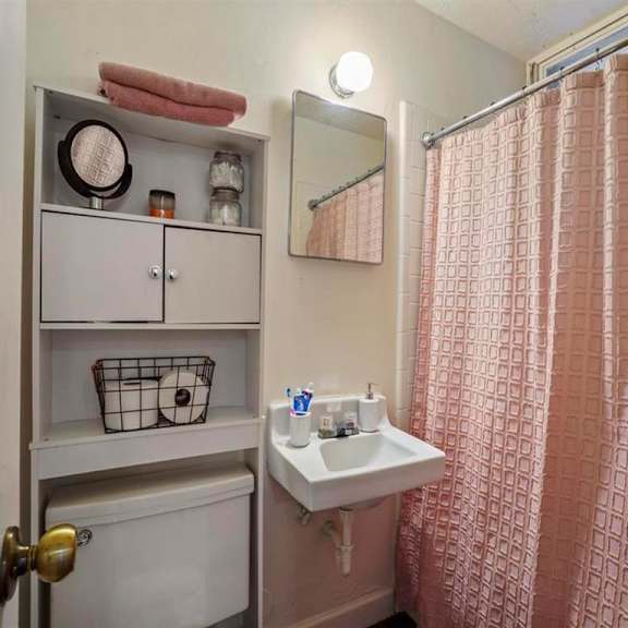 a bathroom with a pink shower curtain and a white sink.