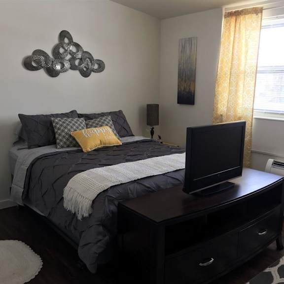 a bedroom with a bed, a television, and a painting on the wall.