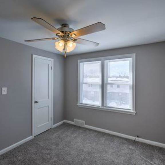 a room with a ceiling fan and a window.