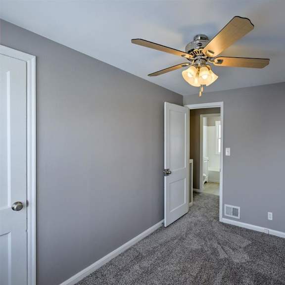 a room with a ceiling fan and carpeted floor.