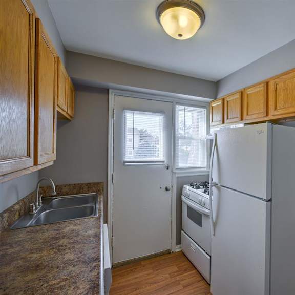 a kitchen with a refrigerator, sink, and stove.