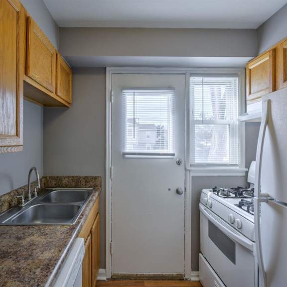 a kitchen with a stove, sink, and refrigerator.