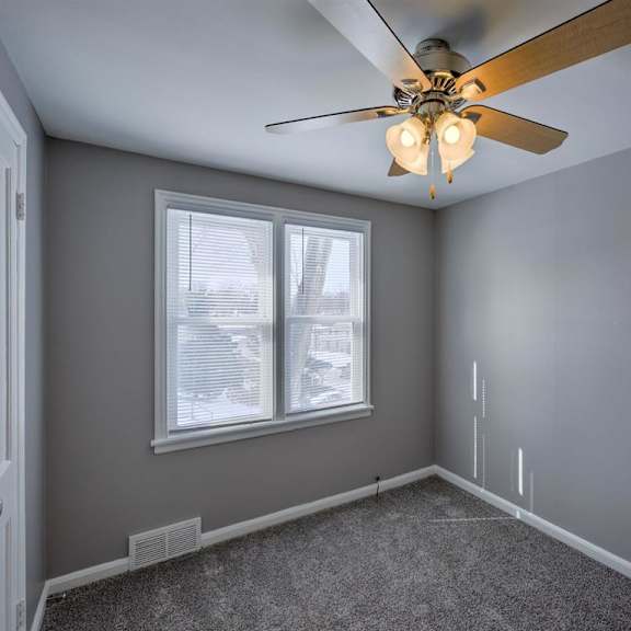 a room with a ceiling fan and a window.