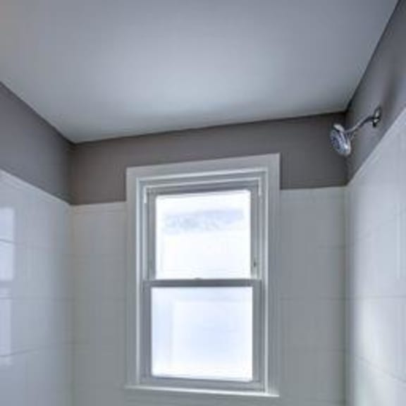 a small window in a tiled bathroom.