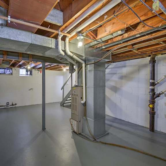 a room with a concrete floor and a staircase leading to the second floor.