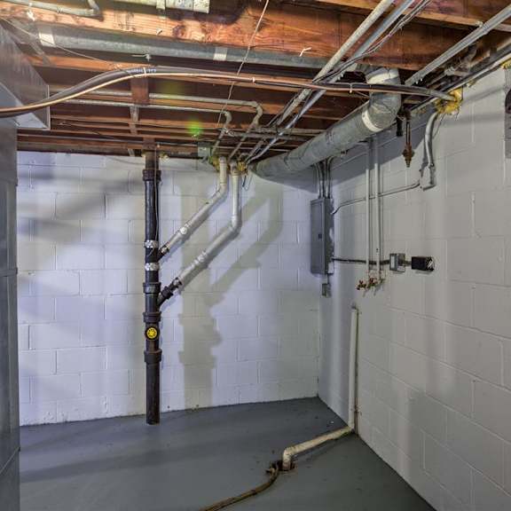 a room with a white wall and a brown pipe.