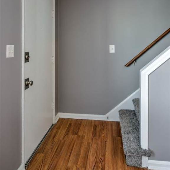 a white door with a silver handle is in a room with grey walls.