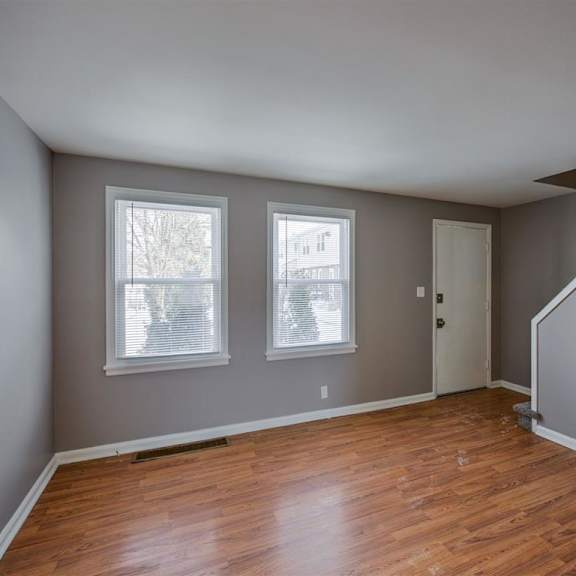 a room with wooden floors and two windows.
