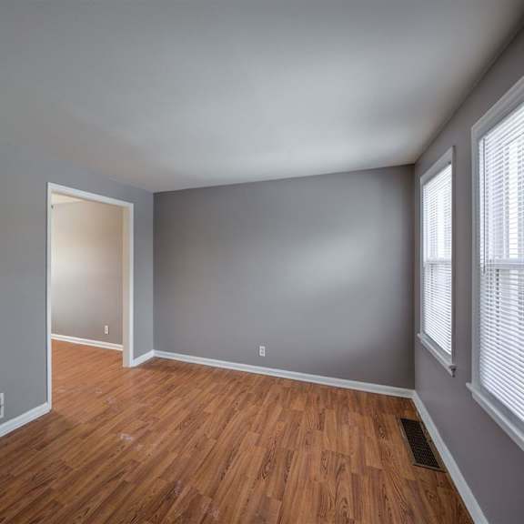 a room with wooden floors and a door on the left.