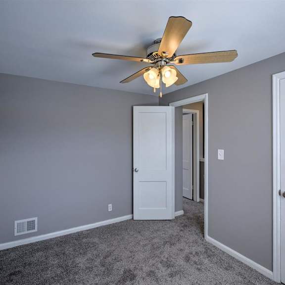a room with a ceiling fan and carpeted floor.