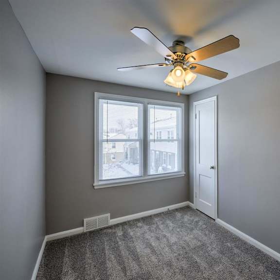 a room with a ceiling fan and a window.