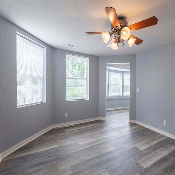 a room with a ceiling fan and wooden flooring.