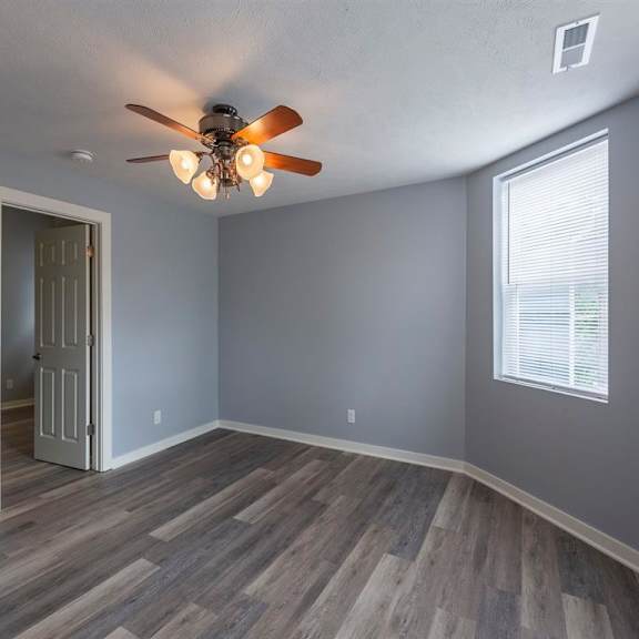 a room with a ceiling fan and wooden flooring.