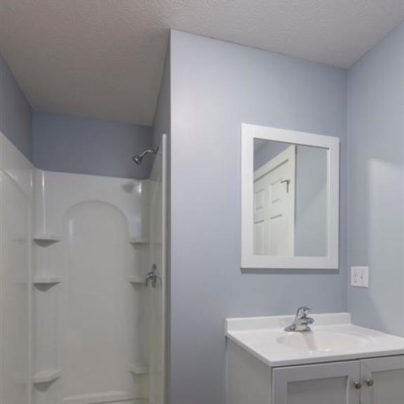 a bathroom with a white sink and a white shower.