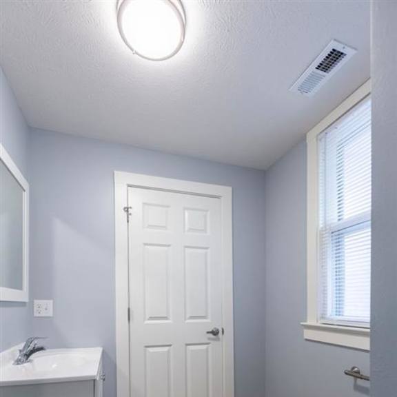 a white toilet sits in a bathroom with a white sink and a white door.